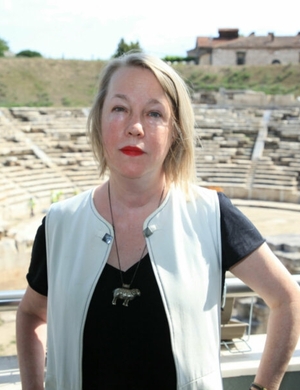 A photo of A.E. Stallings standing in front of the ruins of an ancient theatre.