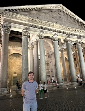 A photo of Daniel Whittle standing in front of the Pantheon, smiling.