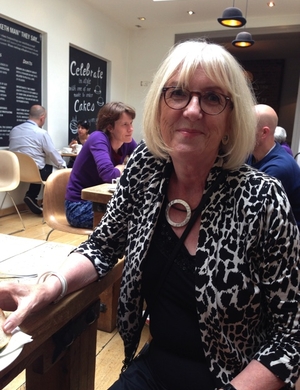 A photo of Karen Caines seated at a table, smiling.