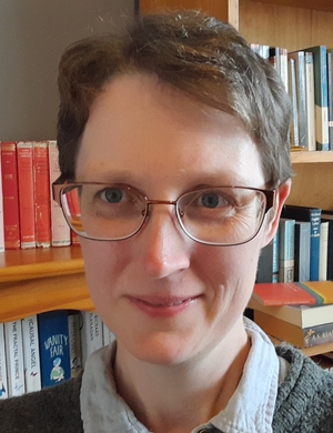 A photo of Helen Slaney standing in front of a shelf of books.