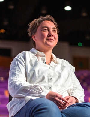 A photo of Stephe Harrop sitting in an auditorium, smiling.