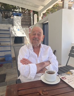 A photo of Oliver Taplin sitting at a coffee table, smiling.