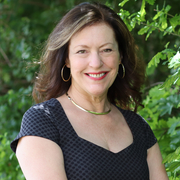 Image of Edith Hall, smiling, standing in front of a leafy background.