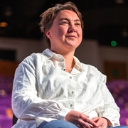 A photo of Stephe Harrop sitting in an auditorium, smiling.