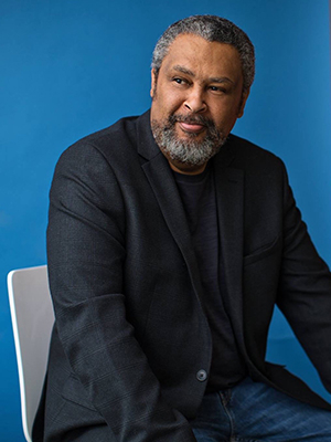 Photo of Kevin Willmott, seated, in front of a blue background